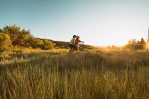 Children and man running and playing on an electric bike in the neighborhood at sunset.