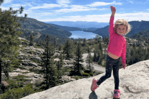young girl on hike above a lake, posing for a photo