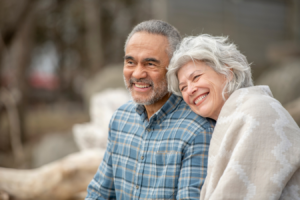 Retired couple sitting on a bench in a park smiling and enjoying the outdoors